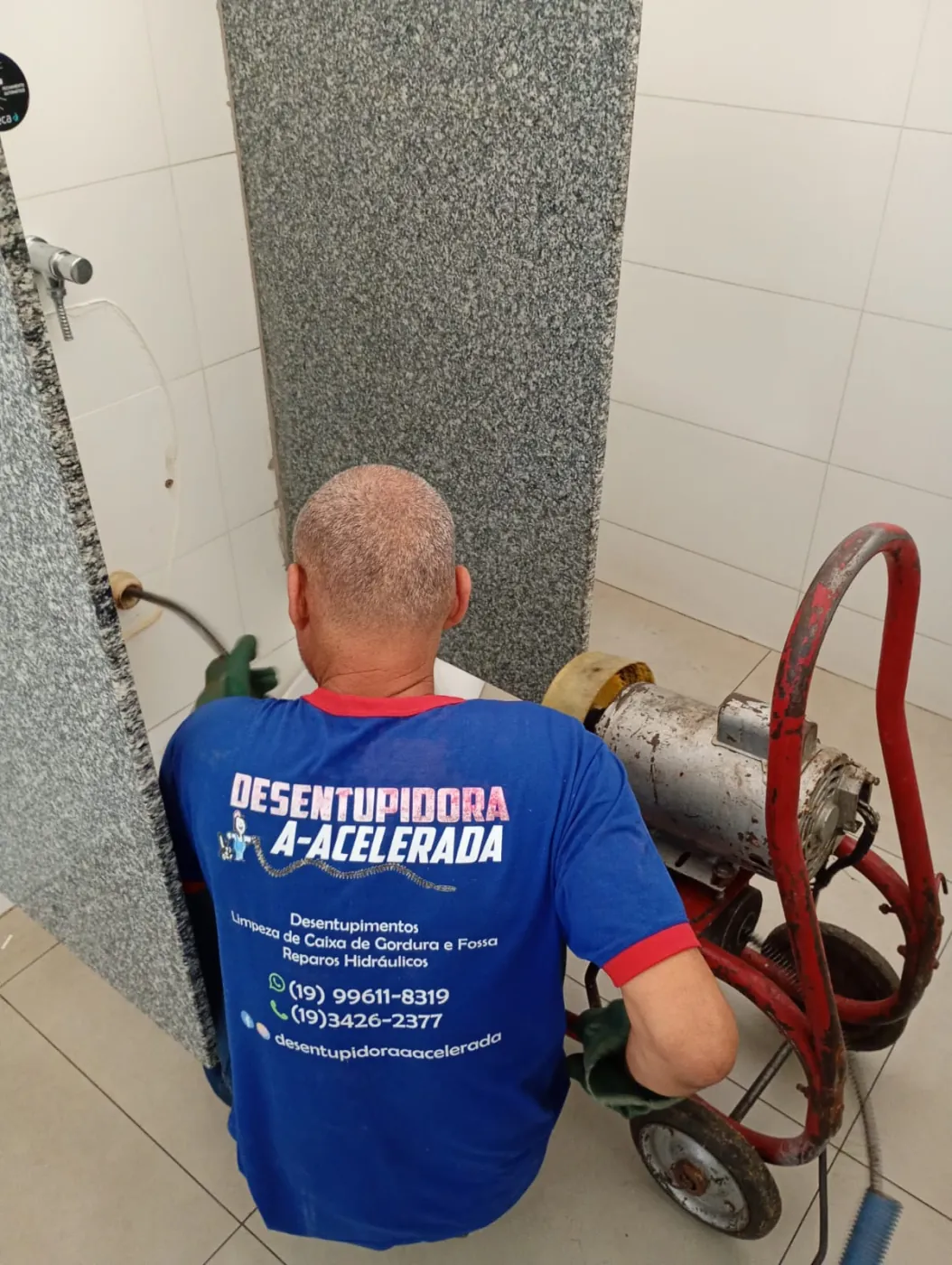 Profissional uniformizado da Desentupidora A-Acelerada operando máquina rotativa